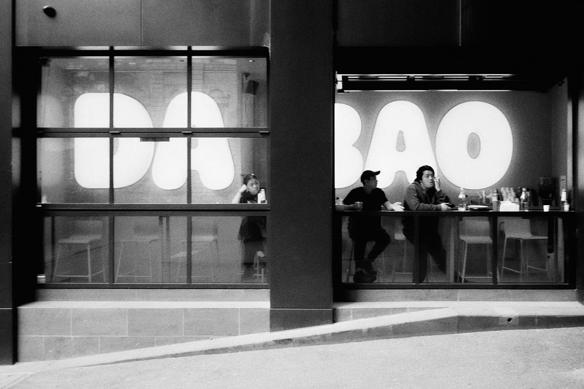 Da Bao restaurant window - three figures separated by architecture
