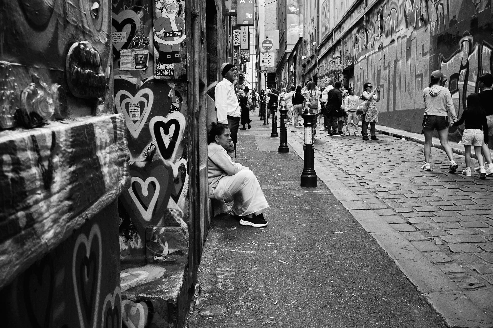 Woman sitting alone surrounded by painted hearts, Hosier Lane